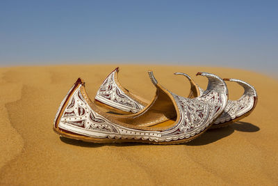 High angle view of shoes on sand at beach against clear sky