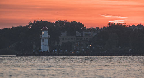 Scenic view of lake by building against sky during sunset