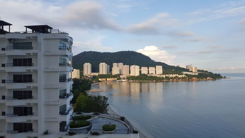 Buildings by sea against sky in city