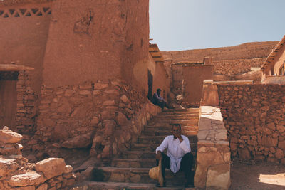 Rear view of people in old building against sky