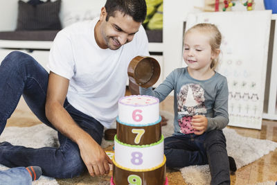 Happy girl stacking number blocks by teacher in classroom