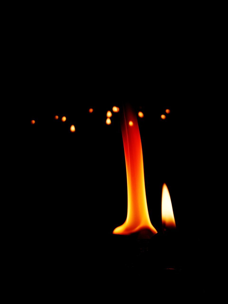 CLOSE-UP OF ILLUMINATED CANDLE AGAINST BLACK BACKGROUND AT NIGHT