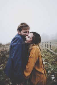 Young couple standing on land against sky