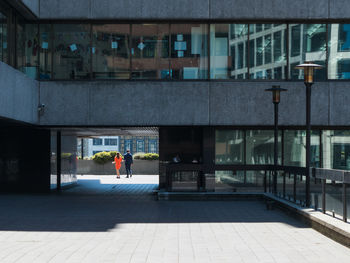 Rear view of people walking on street by building