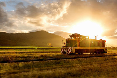 Tractor on field against sky during sunset