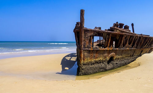 Abandoned boat on beach against clear sky