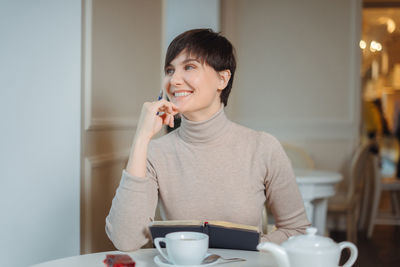 Beautiful woman talking on phone sitting at cafe
