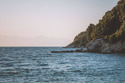 Scenic view of sea and mountains against clear sky