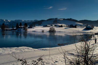 Scenic view of frozen lake by mountains against sky