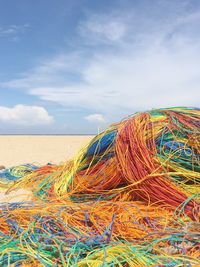 Stack of colorful ropes at beach against sky