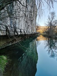 Reflection of bare trees in lake against sky