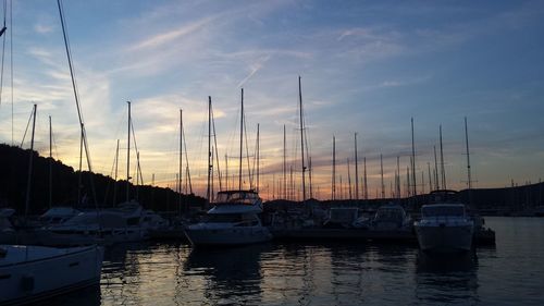 Boats moored at harbor against sky during sunset