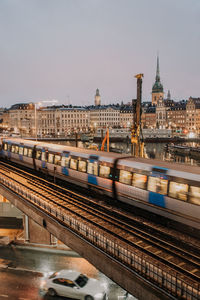 Train on bridge in city against sky