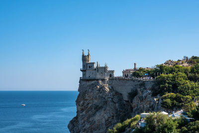 Buildings by sea against clear blue sky