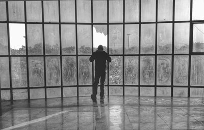 Rear view of man standing against window