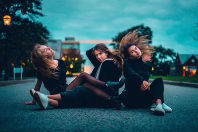 Young woman sitting in park with people in city