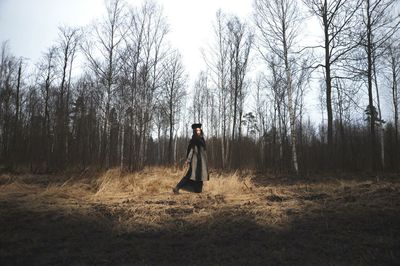 Full length of woman standing on tree trunk in forest