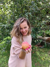 Portrait of smiling woman with apple on tree