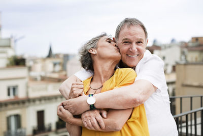 Romantic mature woman kissing senior man on terrace