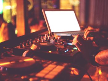 Cropped hands of man operating sound mixer on table