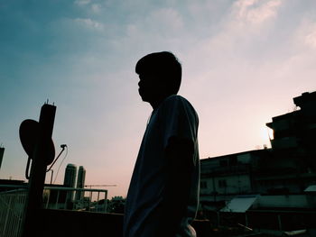 Silhouette man standing by railing against sky during sunset