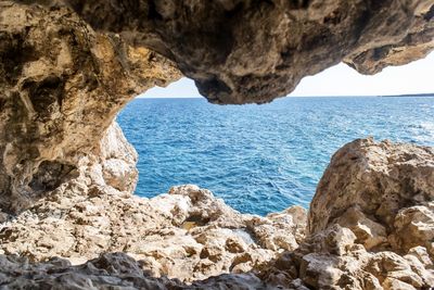 Rock formations by sea against sky