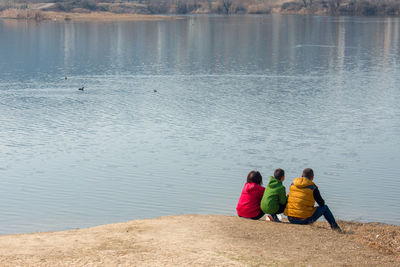 Rear view of family sitting at lakeshore