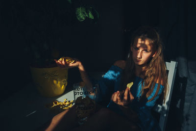 Young woman looking down while sitting on table