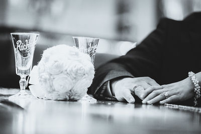 Cropped image of bride and groom by table with wineglasses