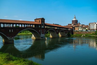 Covered bridge over river against clear blue sky