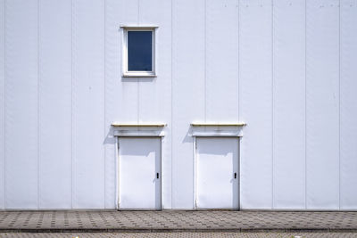 Two white doors in white facade
