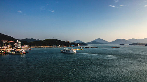 Boats moored on sea by city against clear sky