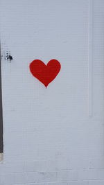 Close-up of red heart shape on white wall