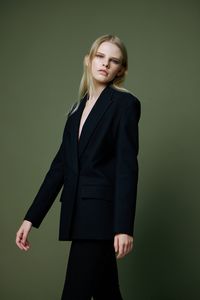 Portrait of young businesswoman standing against gray background