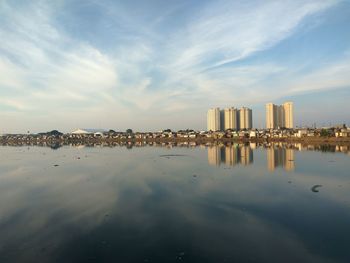 Reflection of buildings in sea against sky