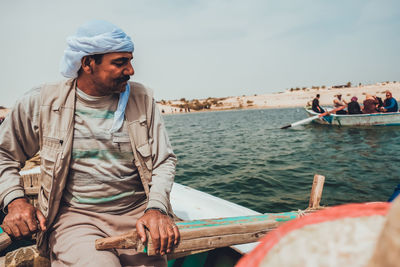 Man sitting on boat sailing in sea against sky