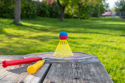 Badminton game rackets and shuttlecock on wooden table with green grass backgroud in the park.