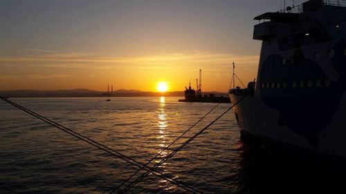 Boats moored at harbor during sunset