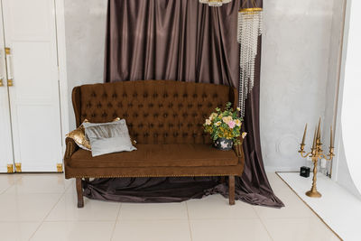 Luxury brown classic sofa with pillows and a bouquet of flowers in a vase in the living room 
