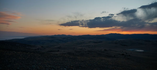 Scenic view of landscape against dramatic sky during sunset