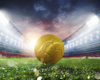 Digital composite image of soccer ball on field against sky