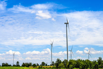 Low angle view of wind turbines against sky