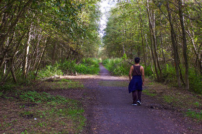 Rear view full length of man walking amidst trees in forest