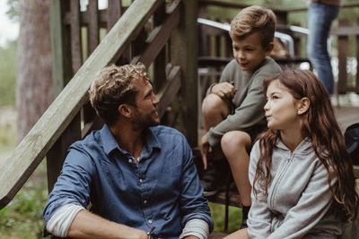 Father and children spending leisure time while sitting on steps during vacation