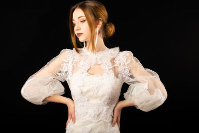 Young woman looking away against black background