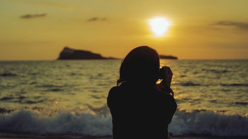 Silhouette woman standing at beach during sunset