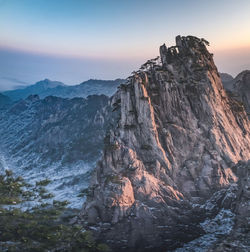 Rock formations by mountain against sky during sunset