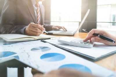 Midsection of business colleague working in office