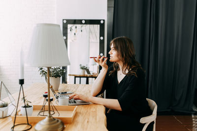 Side view of woman sitting on table