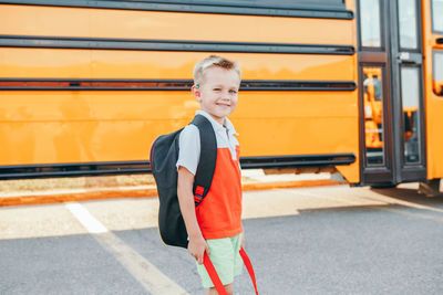 Portrait of smiling boy standing by bus